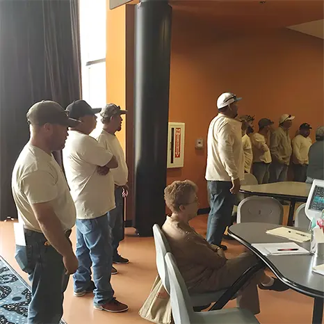 Los Alamos Landscaping team attending a training or meeting in a conference room, standing and seated while engaging with a presentation.